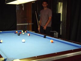 Two men with big cocks are banging a lad on the table